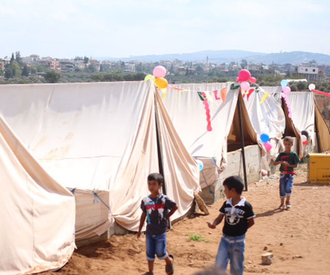 Little boys walking in a Syrian refugee camp.